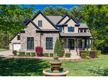 Beautiful stone and stucco home featuring a manicured lawn, lush landscaping and a charming fountain at 546 Little Cove Ln, Lake Wylie, SC 29710