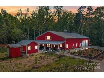 Beautiful red barn-style home with covered patio and professional landscaping at sunset at 574 Crescent Rd, Rockwell, NC 28138