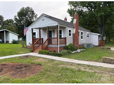 Charming single-story home with a covered front porch, an American flag, and a well-maintained yard at 410 Gann St, Lowell, NC 28098