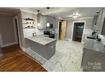 Modern kitchen features granite countertops, stainless steel appliances, and stylish marble floors at 410 Gann St, Lowell, NC 28098