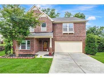 Charming two-story brick home featuring a well-manicured lawn, mature tree, and an attached two-car garage at 1017 Quail Run Ct, Indian Land, SC 29707