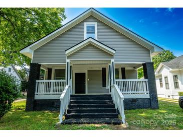 Charming home featuring a welcoming front porch, gray siding, and contrasting black accents on the brick foundation at 112 Hampton St, Chester, SC 29706