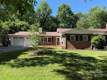 Charming brick home with an attached two-car garage, a well-manicured lawn, and lush trees surrounding the property at 121 33Rd Ne Ave, Hickory, NC 28601