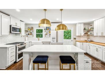 Bright kitchen featuring an island with seating, stylish lighting, white cabinets, and modern stainless steel appliances at 106 Phifer St, Fort Mill, SC 29715