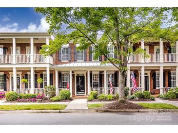 Charming brick townhome with inviting front porch and patriotic American flags on display at 139 Harper Lee St, Davidson, NC 28036