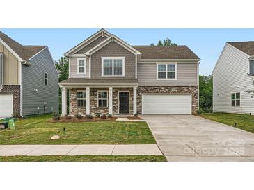 Charming two-story home with stone accents, a covered porch, a two-car garage, and a well-manicured lawn at 1545 Cottage Creek Dr, Bessemer City, NC 28016