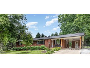 Charming single-story brick home featuring a covered porch and a well-manicured front yard with mature trees at 240 China Grove Rd, China Grove, NC 28123