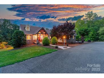 Charming home featuring a stone and siding exterior, covered porch, and mature landscaping at sunset at 560 Blue Sky Dr, Dallas, NC 28034