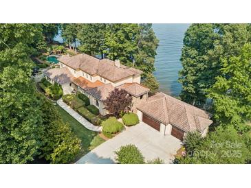 Lakefront home with expansive windows, tile roof, multiple garages, manicured grounds, and waterfront access at 9184 Greenwood Rd, Terrell, NC 28682