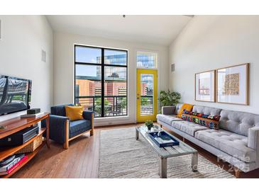 Bright living room boasts a large window, yellow door, and comfortable seating, creating a welcoming atmosphere at 115 E Park Ave # 409, Charlotte, NC 28203