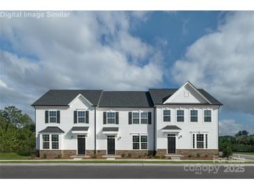 Charming townhome featuring a classic facade, black shutters, and beautiful landscaping at 7633 Griffins Gate Dr, Concord, NC 28025