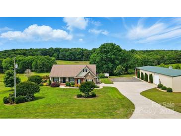 Picturesque aerial view of a home with a large, well-maintained lawn, a long driveway and mature trees at 9950 Foil Rd, Mount Pleasant, NC 28124