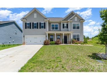 Charming two-story home boasts a manicured lawn, inviting entrance, and a two-car garage at 10045 Carousel Corral Dr, Midland, NC 28107