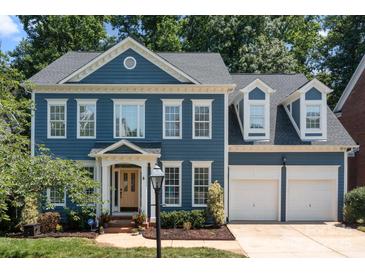 Beautiful two-story blue home featuring an attached two car garage, manicured lawn, and tasteful landscaping at 20324 Middletown Rd, Cornelius, NC 28031