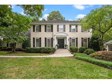 Elegant, two-story home with a classic painted brick facade, black shutters, and professionally landscaped front yard at 2709 Wamath Dr, Charlotte, NC 28210