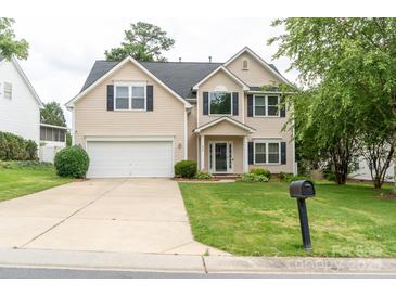 Charming two-story home with a well-manicured lawn and attached garage, painted in neutral beige at 435 Riverwalk Nw Dv, Concord, NC 28027