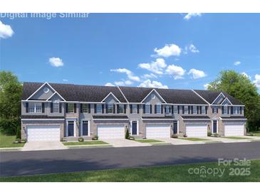 Charming townhouse complex featuring a brick and gray facade with a one car garage on a sunny day at 7335 Childress Dr, Concord, NC 28025