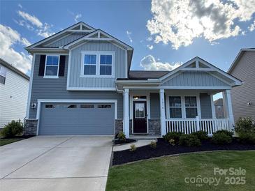 Charming two-story home with gray siding, stone accents, a covered porch, and a two-car garage at 1016 Laggan Ln, Indian Trail, NC 28079