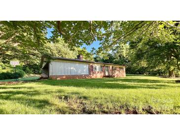 Quaint brick home on a large lot, shaded by mature trees and green grass at 1229 Rocky Face Church Rd, Taylorsville, NC 28681