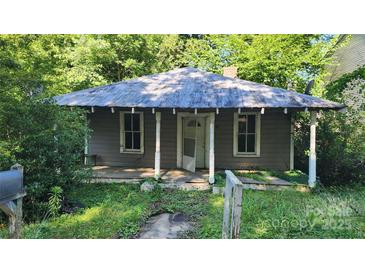 Charming single-story home with front porch, nestled amidst lush greenery and mature trees at 210 Mahan Sw St, Concord, NC 28025
