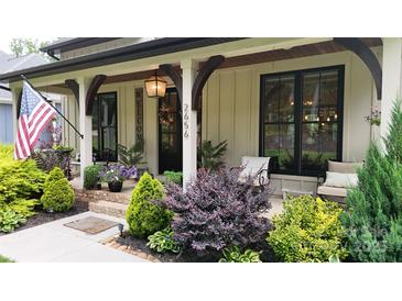 Inviting front porch with beautiful landscaping and craftsman style pillars and warm pendant lighting at 2656 Lee Lawing Rd, Lincolnton, NC 28092