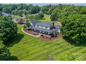 Beautiful home with a well-manicured lawn and mature trees creating an inviting and picturesque setting at 8698 Rocky River Rd, Harrisburg, NC 28075