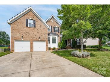 Charming brick home featuring an attached two-car garage and a well-manicured front yard with mature trees at 4392 Sunset Rose Dr, Fort Mill, SC 29708