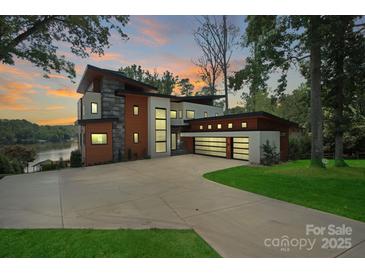 Stunning modern home featuring a spacious driveway, three-car garage, and picturesque lake views at 5930 Midsomer Rd, Charlotte, NC 28214