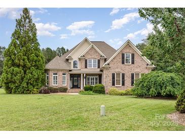 Charming brick home featuring a manicured lawn, lush landscaping, and a classic architectural design at 6057 Erie View Ct, Denver, NC 28037