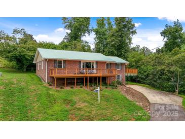 Charming brick home with a green roof, wooden deck, and lush green lawn at 6294 Southlake Dr, Hickory, NC 28601