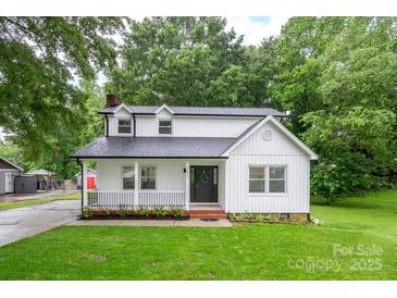 Charming renovated two-story home featuring a welcoming front porch, fresh landscaping, and white board and batten siding at 4633 Old Mill Rd, Gastonia, NC 28056