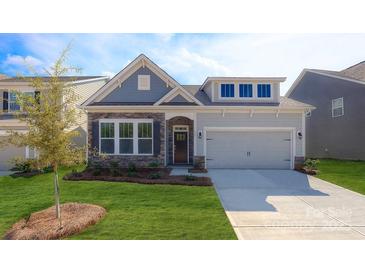 Charming home features a stone facade, gray siding, a manicured lawn, and an attached two-car garage at 3128 Spring Iris Dr, Denver, NC 28037