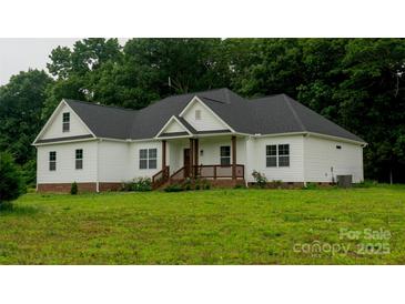 Charming one-story home featuring white siding, a welcoming front porch, and a lush green lawn with beautiful surrounding trees at 4710 Old Pageland Marshville Rd, Monroe, NC 28112