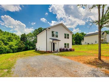 Beautiful white two-story home featuring a gravel driveway and surrounded by lush trees at 415 Kickapoo Ave, Gastonia, NC 28056