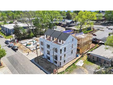 Under construction building showing framing, sheathing, and a new roof surrounded by trees and other buildings at 113 Verbena Ne St # 11, Charlotte, NC 28217