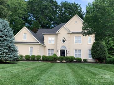 Traditional home featuring manicured lawn, lush landscaping, and charming architectural details at 12711 Duncourtney Ln, Charlotte, NC 28277