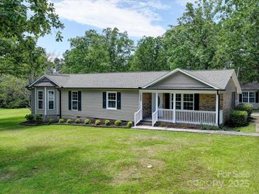 Well-maintained home with inviting front porch and lush landscaping, nestled among mature trees at 1306 Abbey Ct, Lancaster, SC 29720