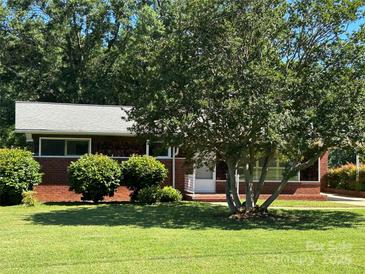 Charming brick home featuring a well-manicured lawn and mature trees, offering great curb appeal at 1412 Beverly Ave, Shelby, NC 28152