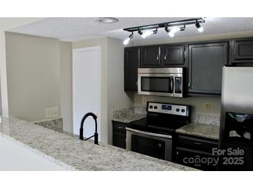 Updated kitchen features granite countertops, black cabinets, and stainless steel appliances at 1604 Arlyn Cir # E, Charlotte, NC 28213