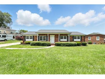 Charming brick ranch home with a well-manicured lawn and black shutters offers great curb appeal at 1735 Hollandale Dr, Gastonia, NC 28054