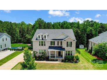 Elegant two-story brick home with a beautifully landscaped front yard, dormer windows, and a covered porch at 319 S San Agustin Dr, Mooresville, NC 28117