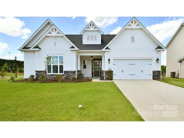 Charming single-story home featuring a manicured lawn, stone accents, and an attached two-car garage at 3924 Dahlia Dr, Harrisburg, NC 28075