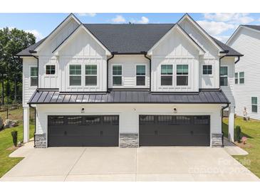 Modern home featuring white siding, a dark roof, black garage doors, and stone accents at 6032 Corbin Woods Ct, Charlotte, NC 28226