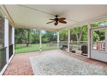 Inviting screened porch with ceiling fan, stone flooring, and view of the expansive backyard at 6908 Lancer Dr, Charlotte, NC 28226