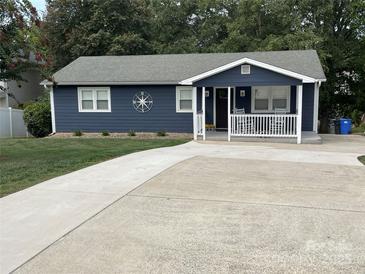 Charming single-story home featuring blue siding, a concrete driveway, and a welcoming front porch with rocking chairs at 132 Marina Ln, Mooresville, NC 28117