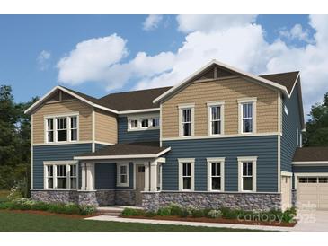 Two-story home featuring stone accents, beige and blue siding, multi-pane windows, and professionally landscaped yard at 2529 Mabel Ln, Monroe, NC 28110