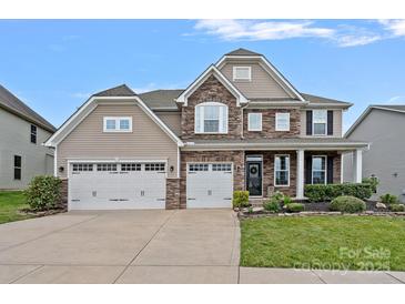 Charming two-story home with a three car garage, stone accents, a manicured lawn and covered front porch at 7339 Millstone Sw Cir, Concord, NC 28025