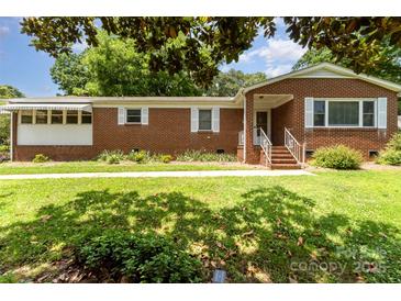 Charming brick home featuring manicured lawn, mature trees, and traditional architectural details at 839 Montford Dr, Charlotte, NC 28209