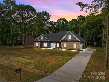 Charming single-story home featuring a stone and gray facade with a welcoming front yard and long driveway at 209 Stafford Estates Dr, Salisbury, NC 28146