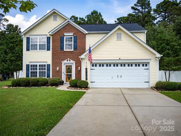 Inviting two-story home featuring yellow siding, brick accents, blue shutters and a well-manicured front yard at 4113 Edgeview Dr, Indian Trail, NC 28079